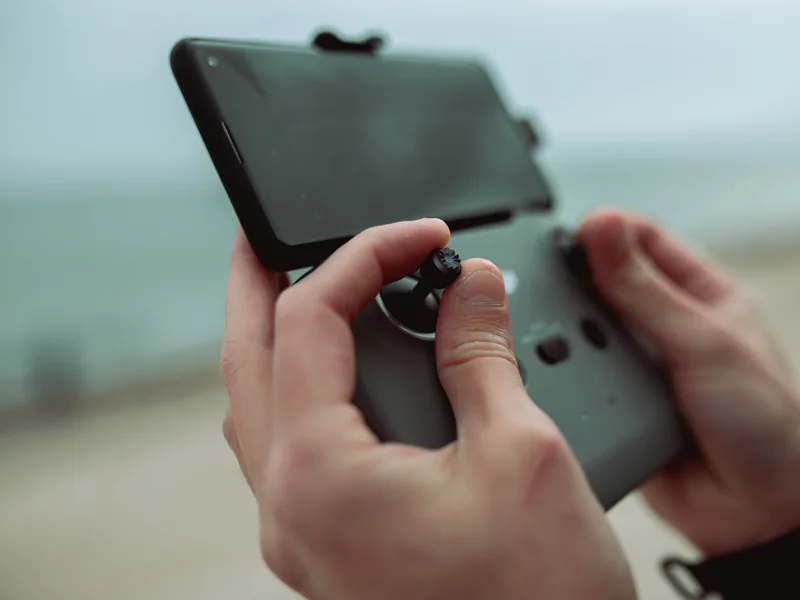 Hands holding a drone controller with a mounted mobile device