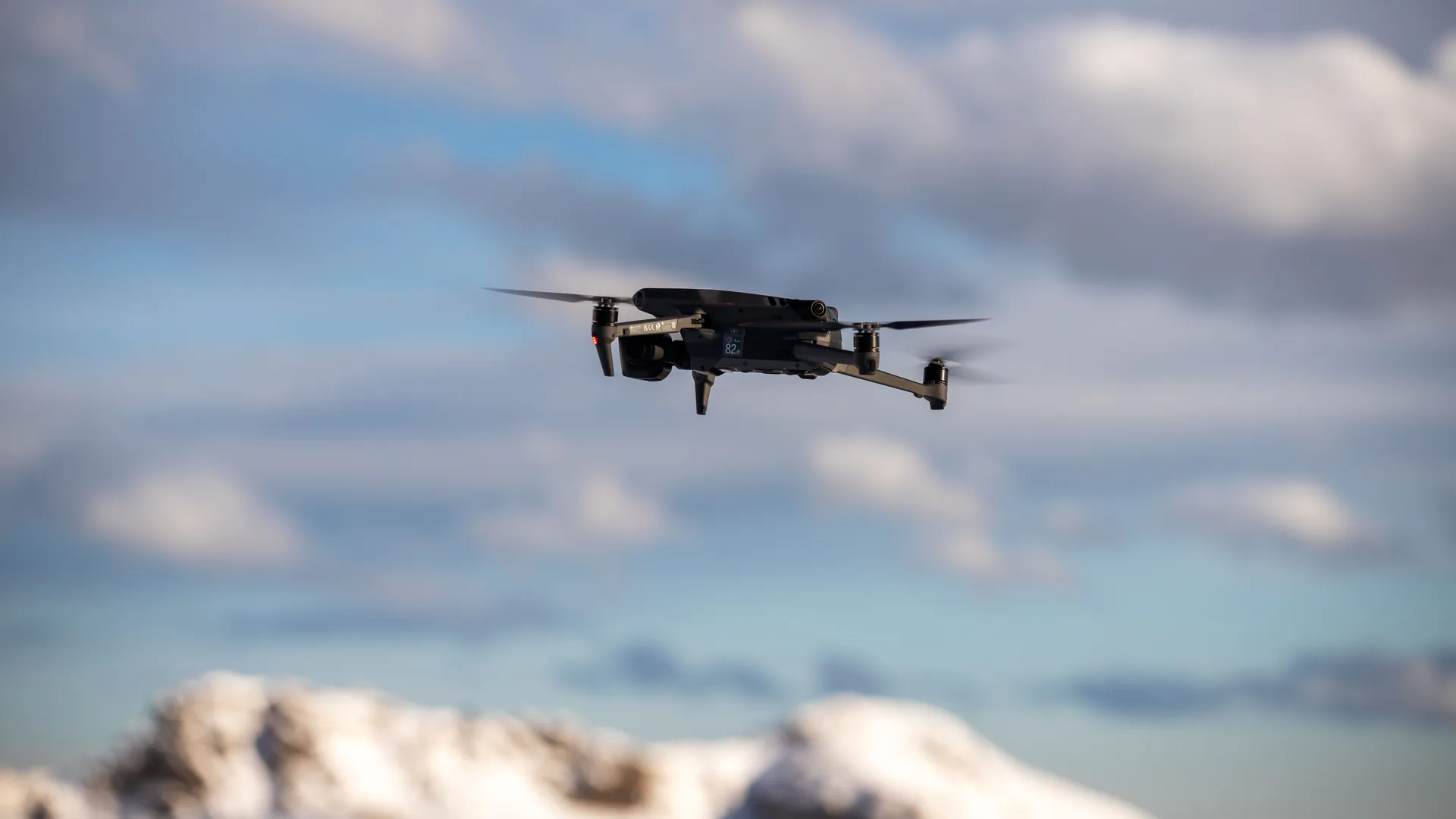 A quadcopter flying against a cloudy sky