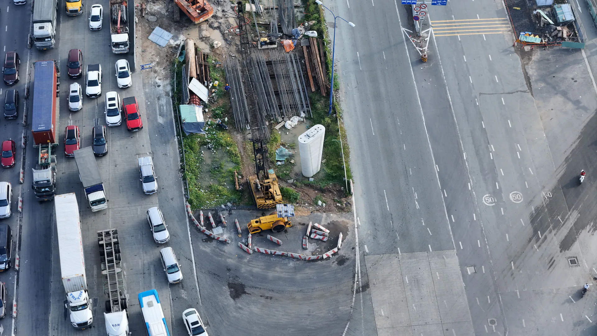 Vehicles queued beside an active road construction area seen from above